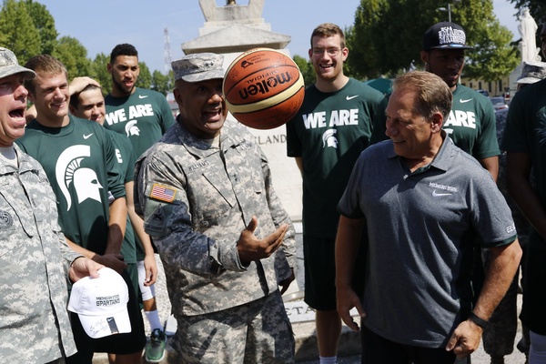 Tom Izzo and MSU basketball team watching a soldier doing tricks with a basketball.